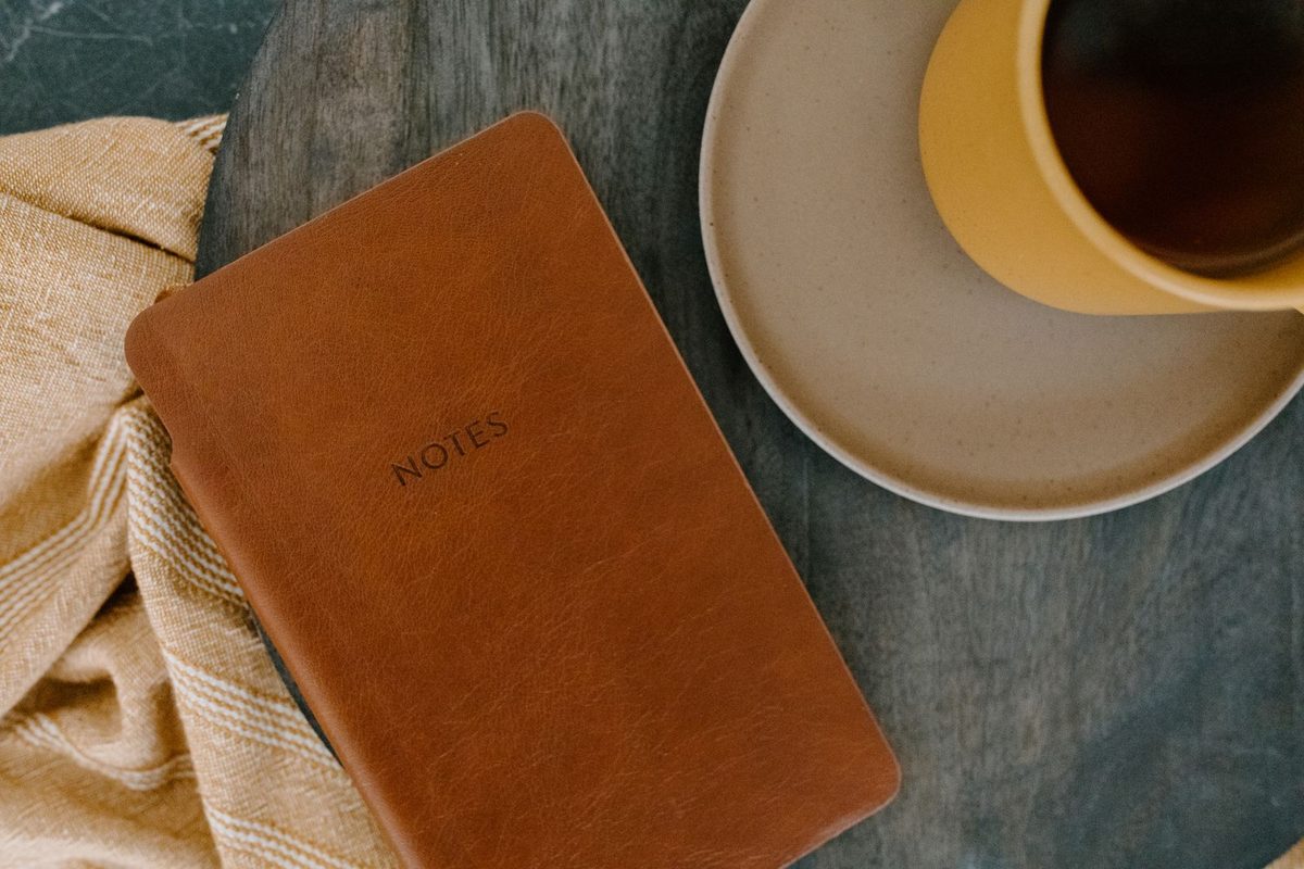 Leather notebook beside a cup of coffee